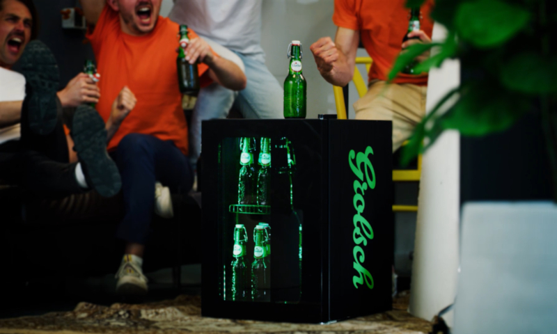 Mensen juichen in het oranje achter de Grolsch beugelkoelkast